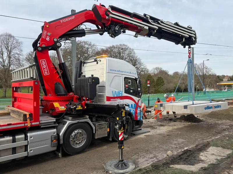 WB Services Volvo with Fassi F1050 crane lifting a concrete slab on site