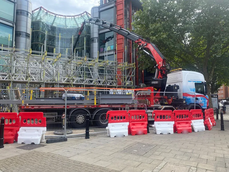 WB Services Scania with Fassi crane lifting beside scaffolding on a city street