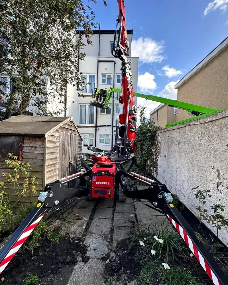 Jekko SPX532 spider crane set up on a narrow rear garden path between a shed and a wall